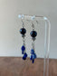 Pair of blue beaded earrings on a clear stand with a neutral background